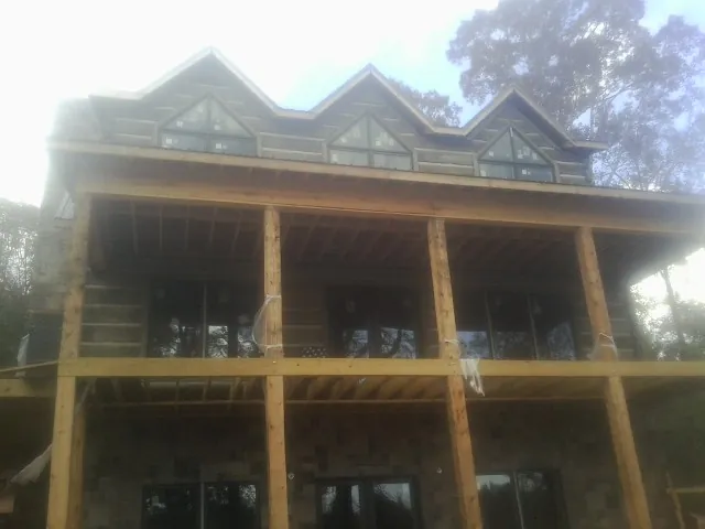 Dormers and porch framing on a large log home under construction — Roof Coating work by our crew in Savannah