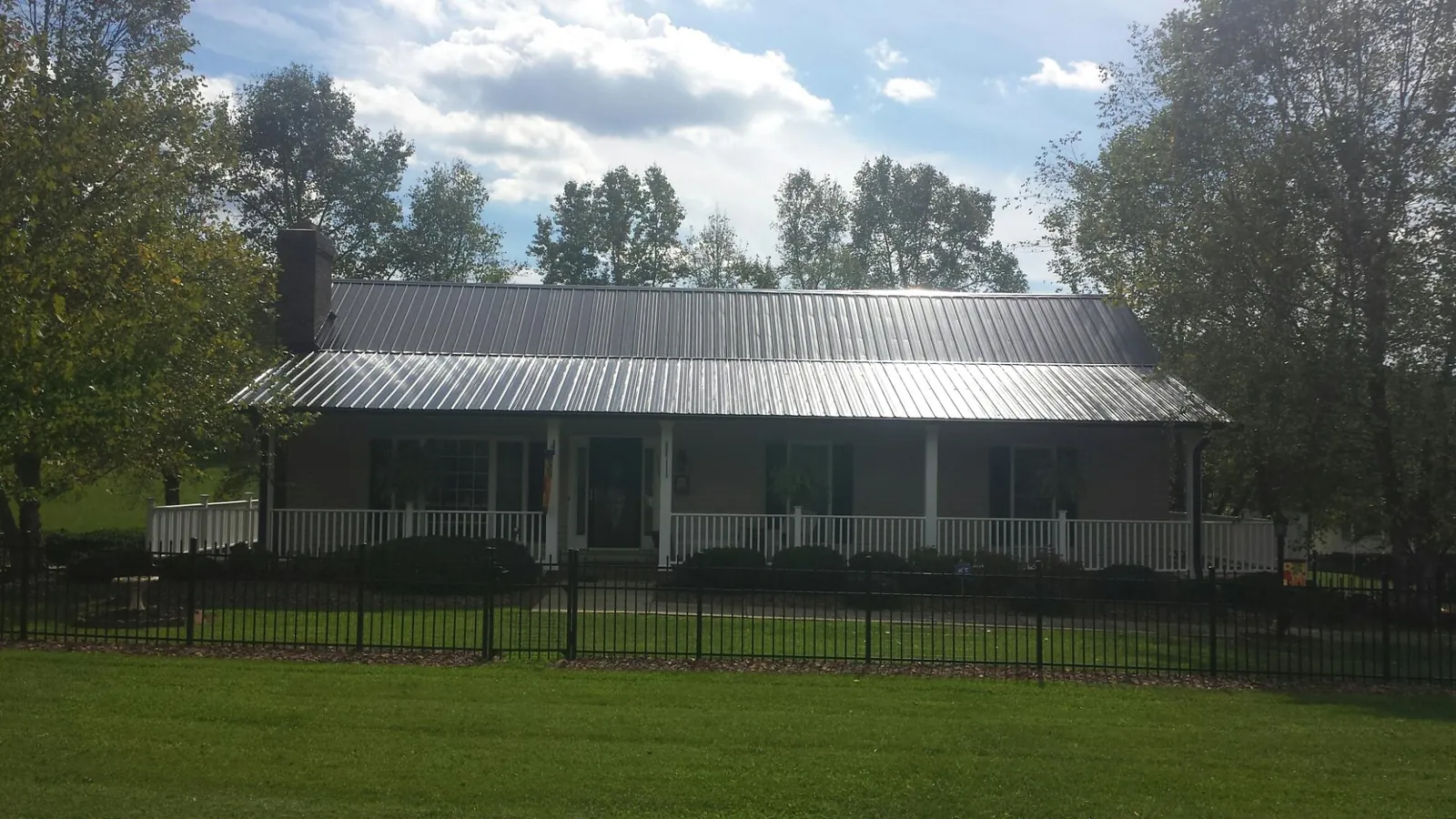 Gray metal roof on a brick ranch with a full width front porch — Gutter Guard Installation work by our crew in Savannah